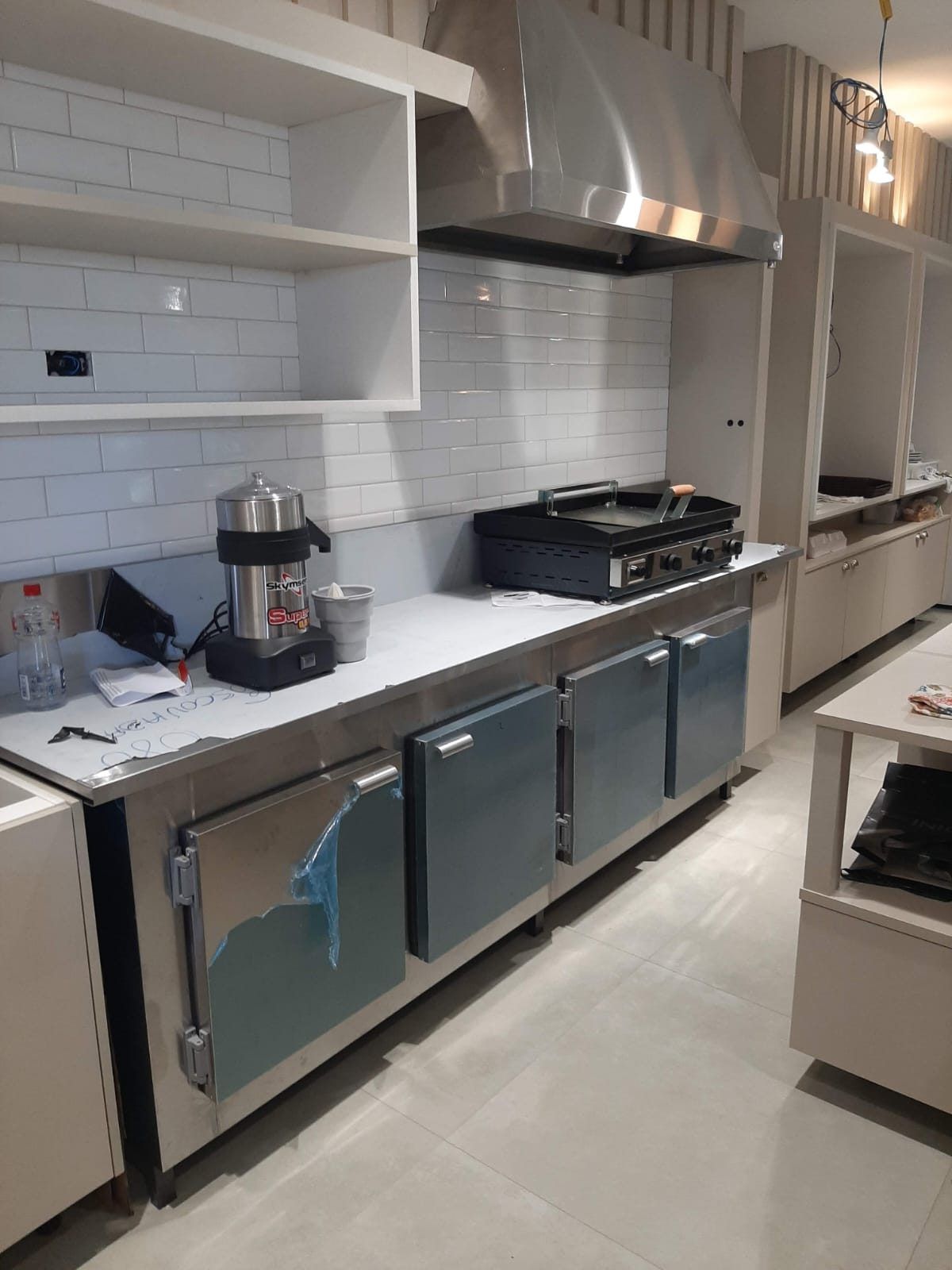 Bancada refrigerada em aço inox com portas fechadas instalada na linha de produção da cozinha